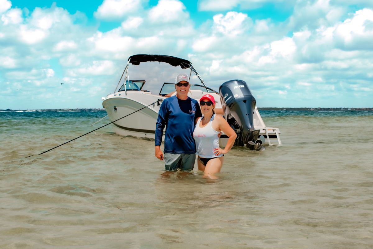 a couple standing in the ocean in front of their boat near Clearwater Beach Florida