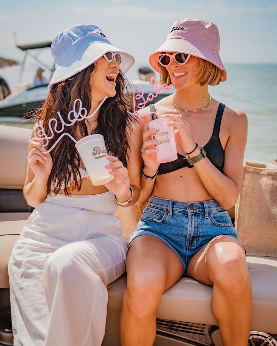 two girls on bach boats cruise with bachlorette themed hats cups and straws